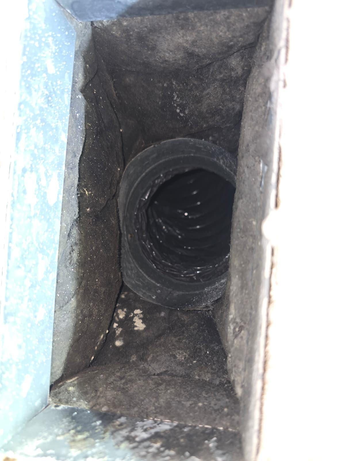 Una bota de rejilla rectangular apelmazada de polvo, con el collarín negro de un ducto flexible encajado en ella